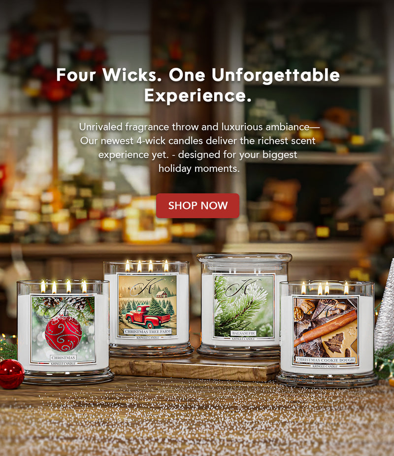 Four wick candles with holiday-themed labels on a decorative surface.