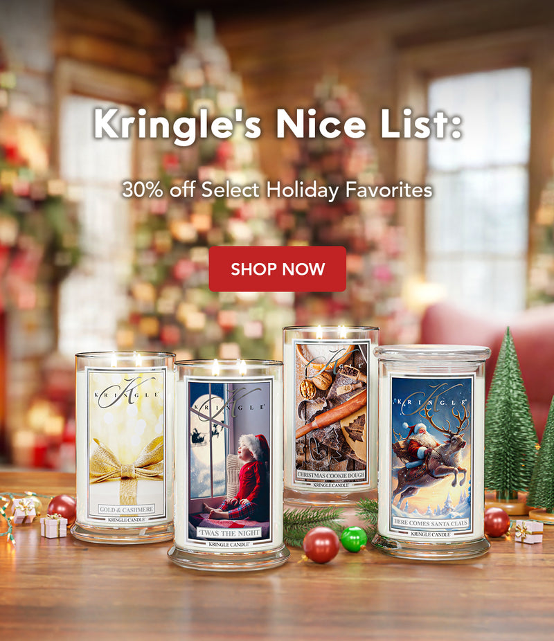 Four Kringle Candle containers on a table with a festive background, featuring a Christmas tree and decorations.