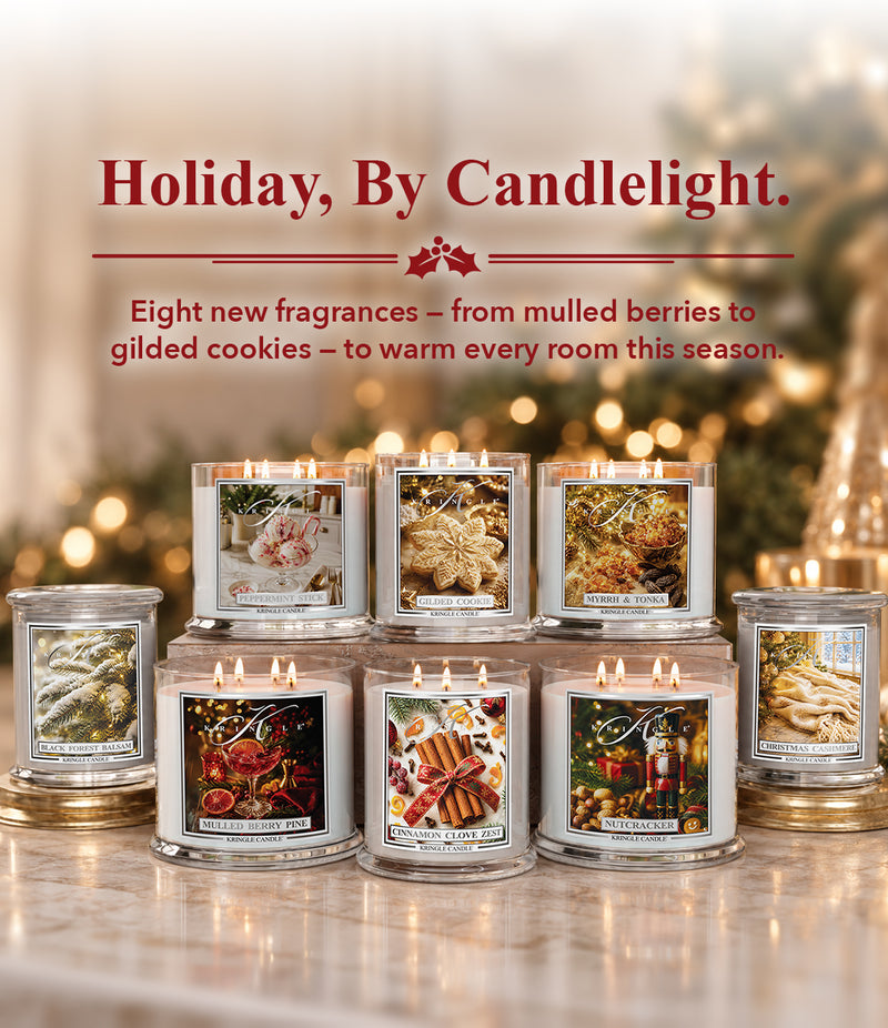 A group of eight lit holiday-themed scented candles in clear glass jars with silver lids, arranged on a marble surface with a warm, blurred festive background. Promotional text at the top reads 'Holiday, By Candlelight.