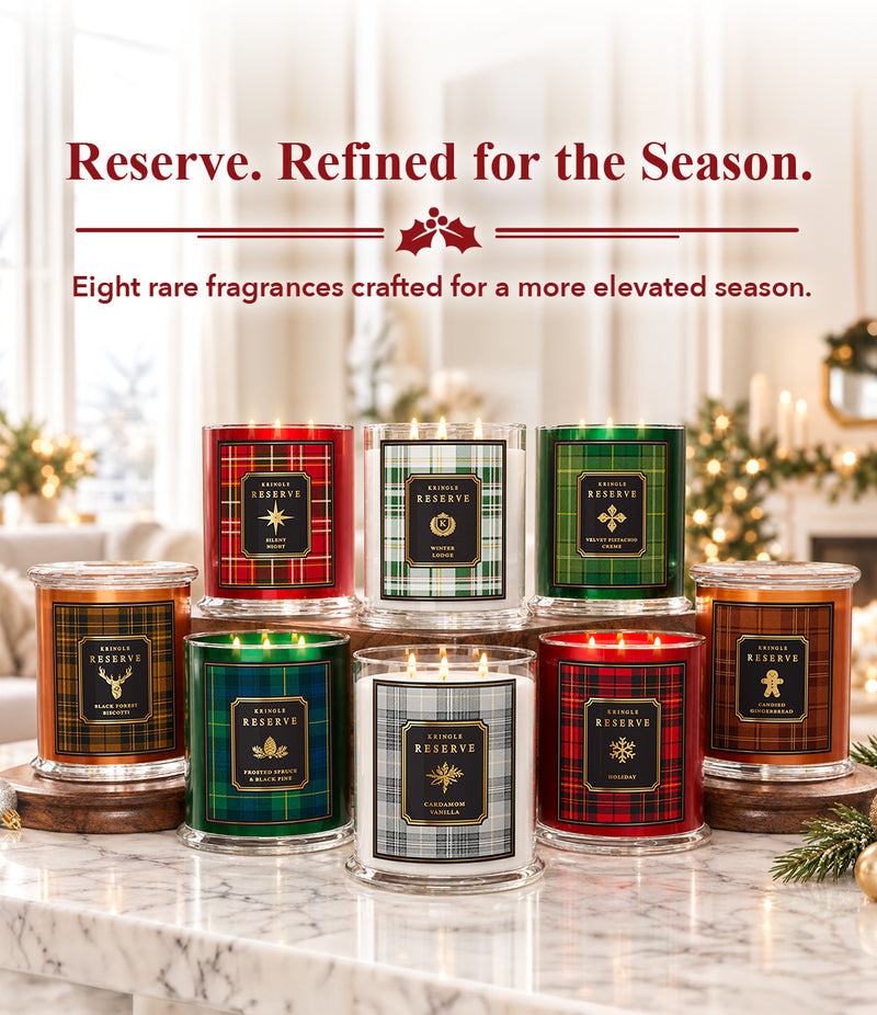 Eight scented candles in clear glass jars with lids, arranged on a marble countertop in a softly lit holiday home setting. Red and dark text at the top reads, 'Reserve.