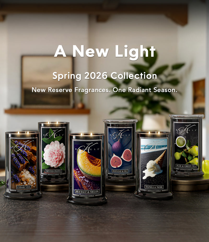 Collection of candles with decorative labels on a wooden surface, featuring 'A New Light' Spring 2026 Collection text.