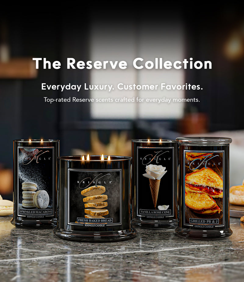 Four candles from The Reserve Collection on a marble surface with a blurred background.