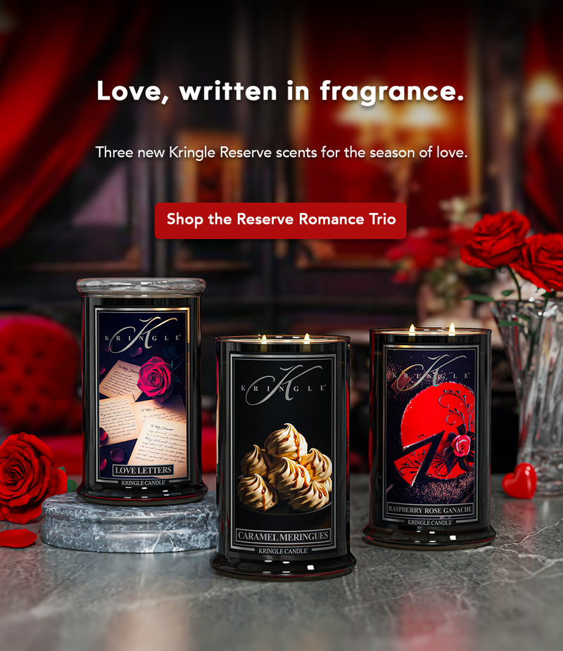 Three Kringle Reserve candles with romantic packaging on a table with red roses.