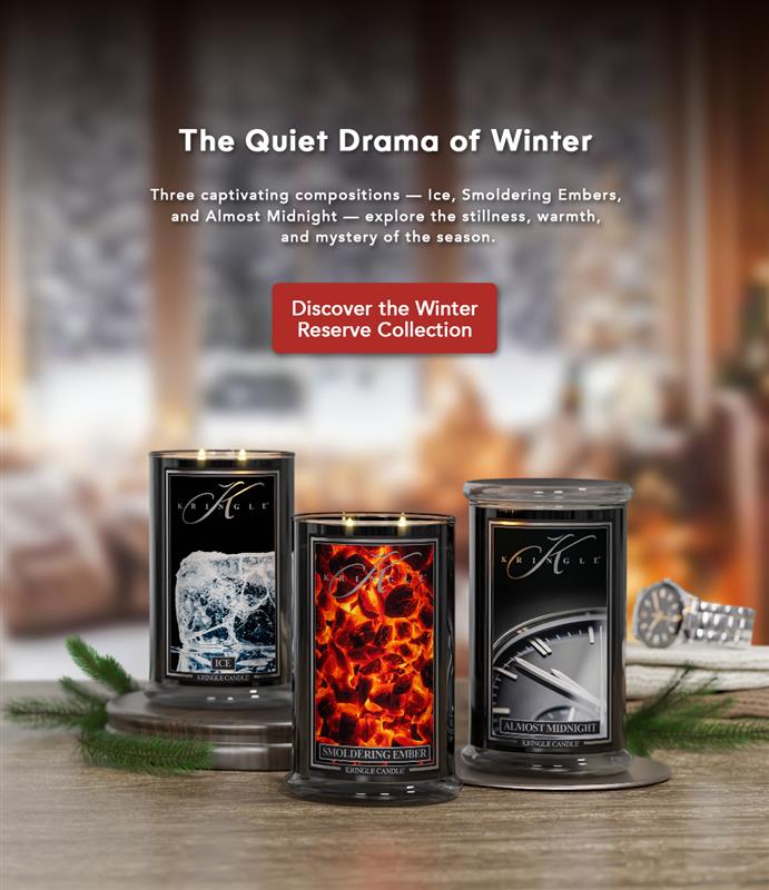 Three candles from the Winter Reserve Collection on a wooden surface with a fireplace in the background.