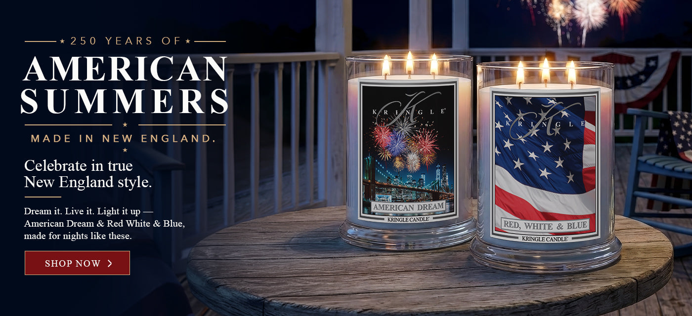 Kringle Candle 250 Years of American Summers banner featuring American Dream and Red, White & Blue 3-wick candles on a wooden table on a porch at night with fireworks and patriotic bunting — Shop Now