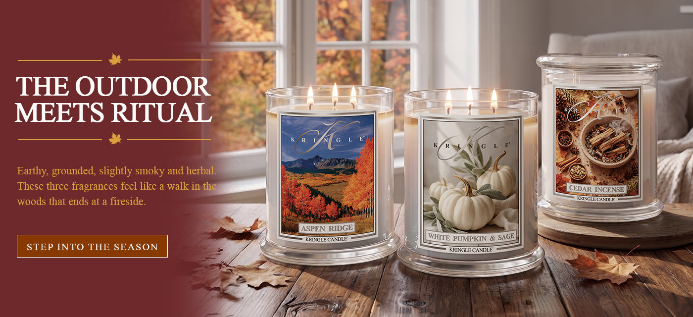 Kringle Candle fall banner featuring three 3-wick candles — Aspen Ridge, White Pumpkin & Sage, and Cedar Incense — displayed on a wooden table by a window with autumn foliage, with text 'The Outdoor Meets Ritual' and a 'Step Into the Season' button
