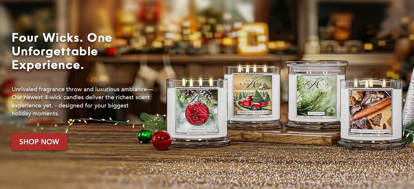 Four wick candles with holiday-themed labels on a wooden surface.