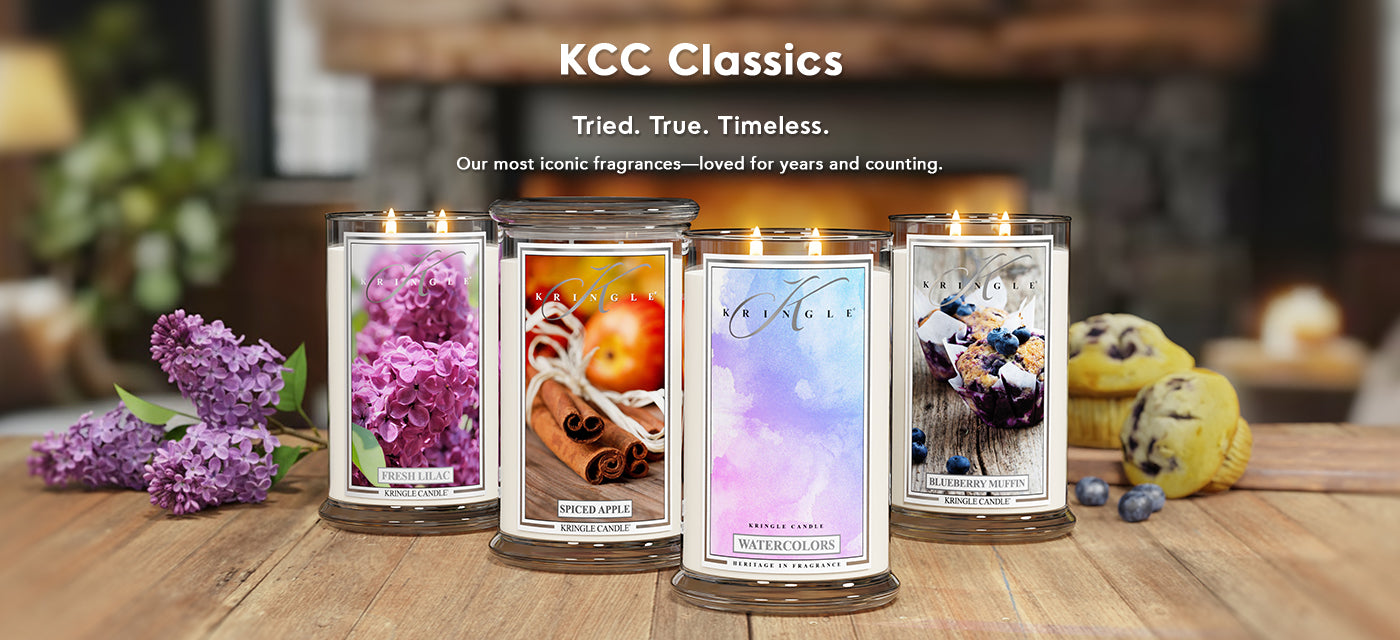 Four KCC Classics candles on a wooden surface with a blurred background