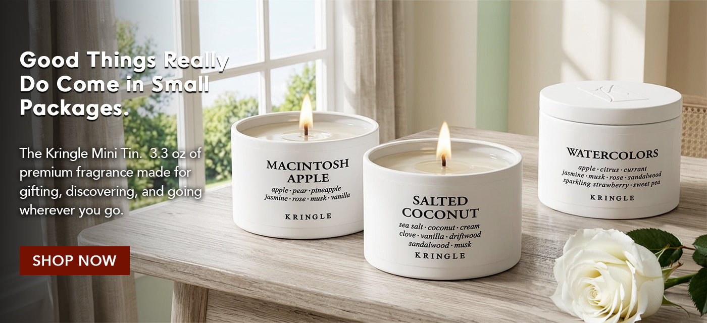 Three Kringle Candle containers on a wooden surface with a window in the background