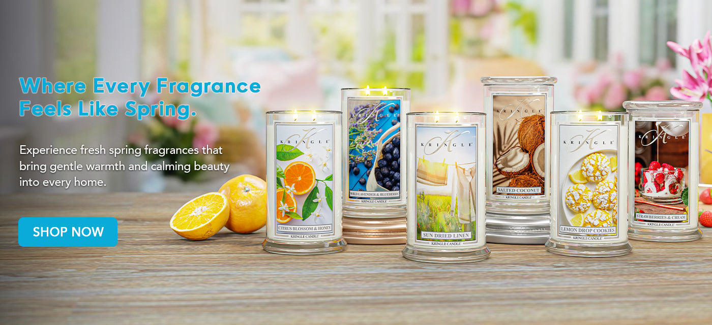 Assorted candles with spring-themed packaging on a wooden surface.