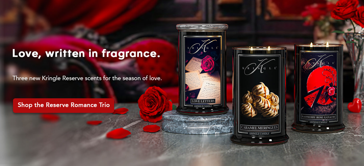 Three Kingle Reserve candles on a reflective surface with red roses and decorative elements.