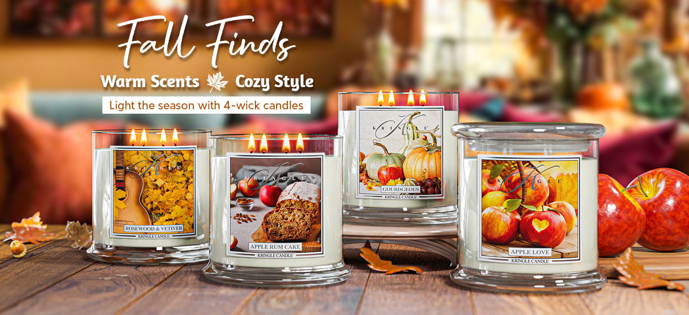 Four fall-themed 4-wick candles on a wooden surface with pumpkins and apples.