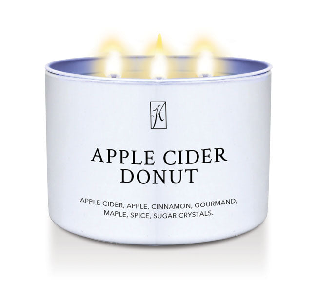 Candle in a white container labeled 'Apple Cider Donut' with flames on a white background