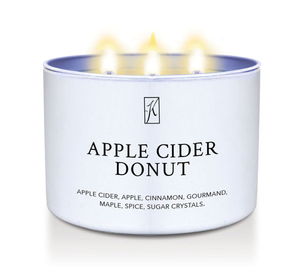 Candle in a white container labeled 'Apple Cider Donut' with flames on a white background
