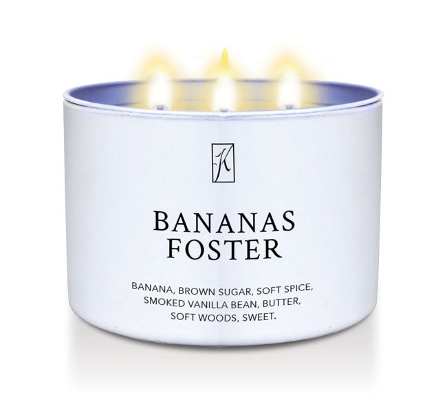 Candle in a container labeled 'Bananas Foster' with a logo on a white background