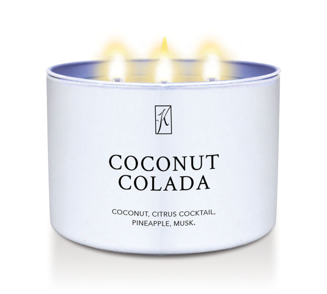 Candle in a white tin container labeled 'Coconut Colada' with flames on a white background