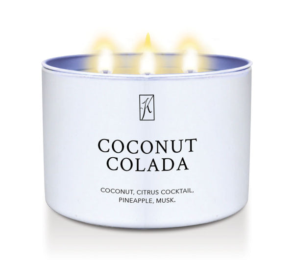 Candle in a white tin container labeled 'Coconut Colada' with flames on a white background