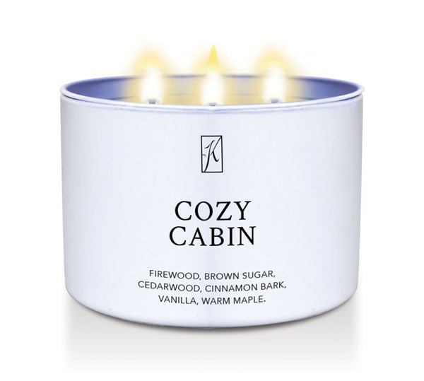 Candle in a white container labeled 'Cozy Cabin' with flames on a white background