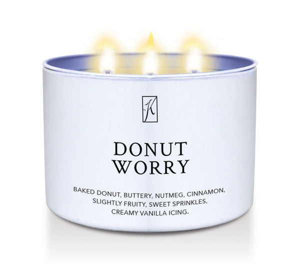 Candle in a white container labeled 'Donut Worry' with flames on a white background