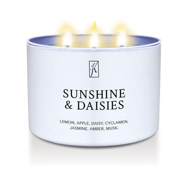 Candle in a white tin container labeled 'Sunshine & Daisies' with flames on a white background