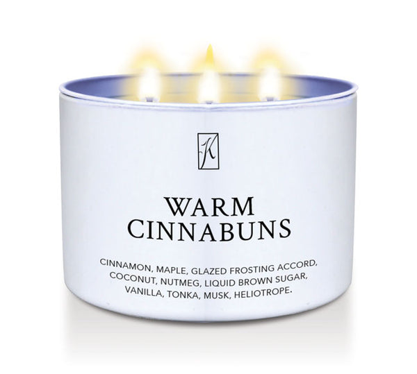 Candle in a white container labeled 'Warm Cinnabuns' with a logo on a white background