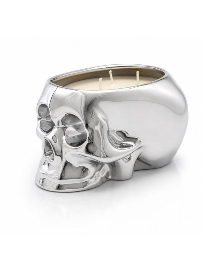 A metallic silver skull-shaped candle holder with three wicks, filled with cream-colored wax, set against a clean white background.
