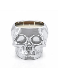 A skull-shaped candle holder made of polished silver-toned metal, filled with cream-colored wax and featuring three wicks, set against a plain white background.