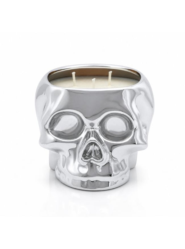 A skull-shaped candle holder made of polished silver-toned metal, filled with cream-colored wax and featuring three wicks, set against a plain white background.
