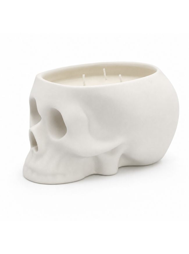 A white ceramic skull-shaped candle holder with three wicks, photographed on a seamless white background.