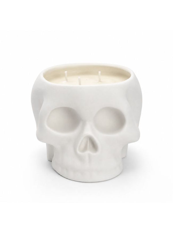 A white skull-shaped candle holder with three wicks, filled with white wax, set against a plain white background.