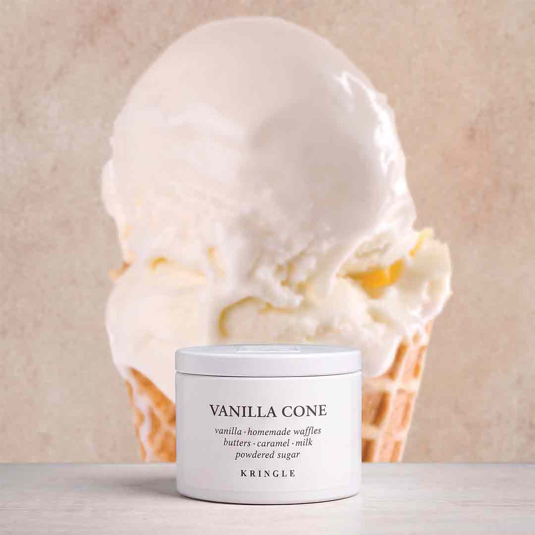A white jar of KRINGLE Vanilla Cone flavored powdered sugar placed in front of a large vanilla ice cream cone on a light beige background.