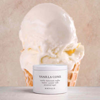 A white jar of KRINGLE Vanilla Cone flavored powdered sugar placed in front of a large vanilla ice cream cone on a light beige background.