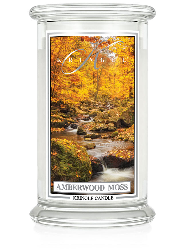 Unlit Amberwood Moss candle with two wicks. Label shows a forest stream surrounded by autumn trees and mossy rocks.