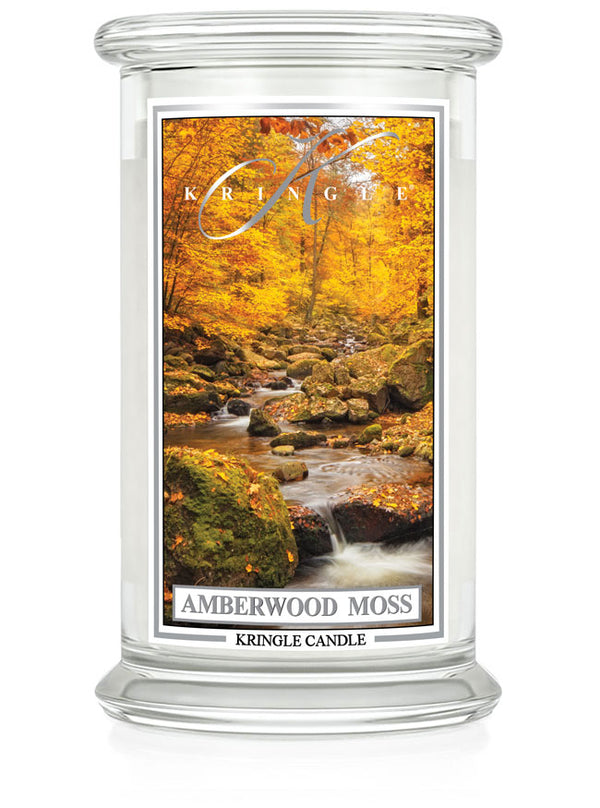 Unlit Amberwood Moss candle with two wicks. Label shows a forest stream surrounded by autumn trees and mossy rocks.