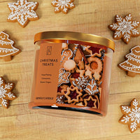 Kringle Candle Christmas Treats candle surrounded by gingerbread cookies on a wooden surface