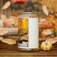 Kringle Candle with 'Amberwood Moss' candle on a wooden surface with a blurred autumn-themed background.