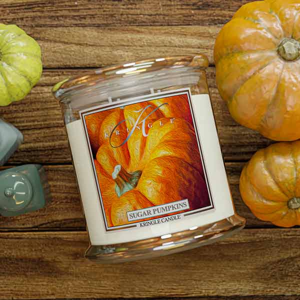 Kringle Candle sugar pumpkins jar on a wooden surface with pumpkins around