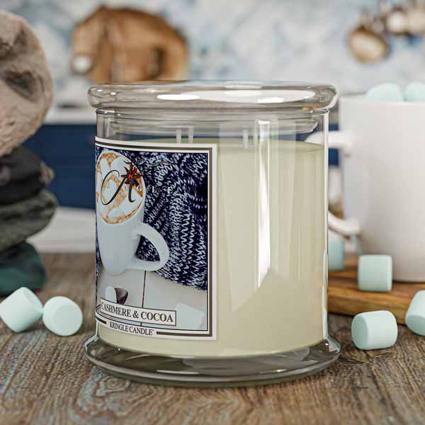 Candle with a 'Marshmellow & Cocoa' label on a wooden surface with marshmallows.