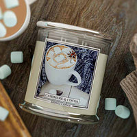 Kringle Candle Cashmere & Cocoa candle on a wooden surface with marshmallows and a hot chocolate cup.
