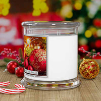 Decorative candle with festive design on a wooden surface with Christmas decorations.