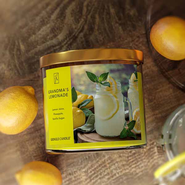 Candle labeled 'Grandma's Lemonade' with lemons around on a wooden surface