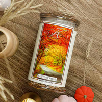 Kringle Candle with 'Autumn Road' design on a wooden surface with blurred autumn-themed background