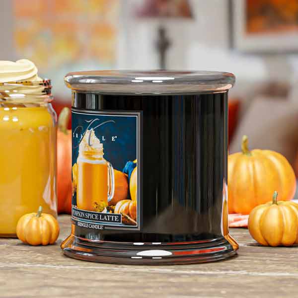 Candle jar labeled 'Pumpkin Spice Latte' with pumpkins and a blurred background