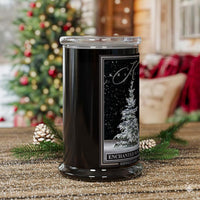 Decorative candle with a Christmas tree design on the label, placed on a surface with festive decorations.