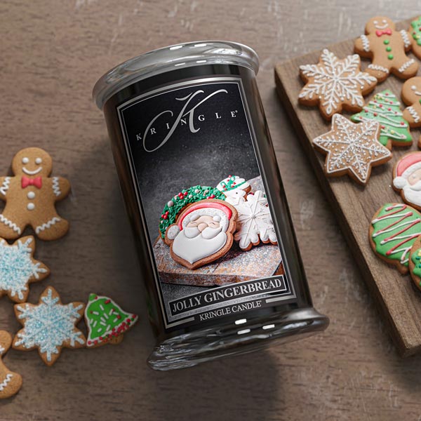 Kringle Candle with gingerbread-themed packaging surrounded by decorated cookies on a wooden surface