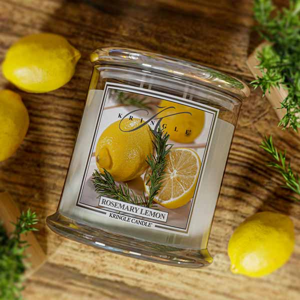 Lit Kringle Candle 4-wick  in Rosemary Lemon scent on a wood background and label showing lemons and rosemary.