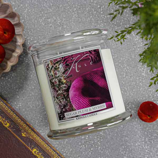 Kringle Candle with 'Sugar Plum & Myrrh' label on a textured surface with decorative elements.