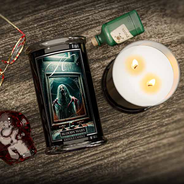 Halloween Candle labeled 'Bloody Mary' next to a lit candle on a wooden surface