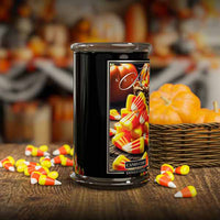Candle with candy corn design on a wooden table with pumpkins in the background