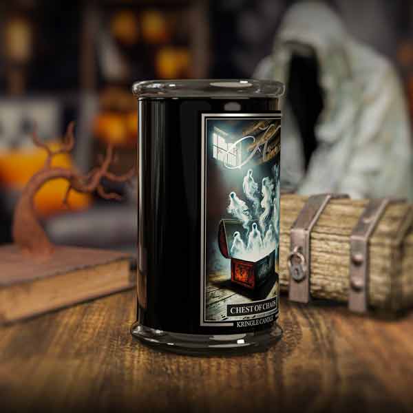Candle in a black container with a ghostly design on a wooden surface